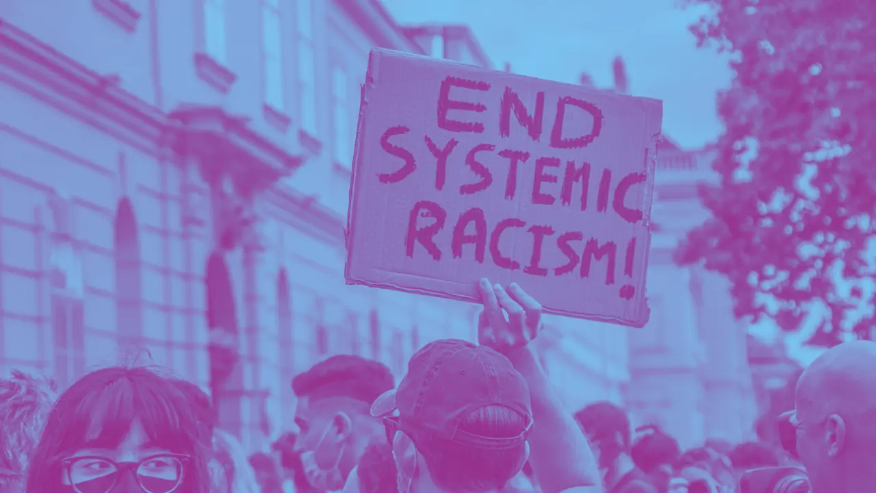 Teilbild einer Demonstration mit einem Pappschild "End Systemic Racism!"